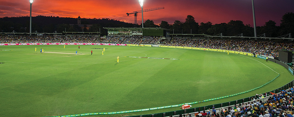 A packed crowd at Manuka Oval watching a 20-20 cricket match.