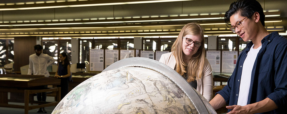  Students investigate a globe at the Menzies Library.