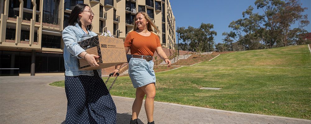 Female students carry their belongings as they walk between Wright and Bruce Hall, at the Australian National University.