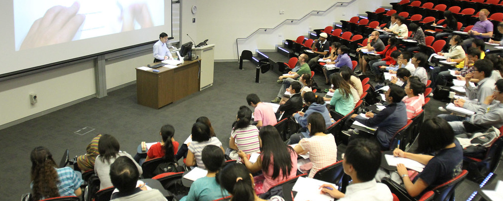 Students sit in a lecture hall and take notes