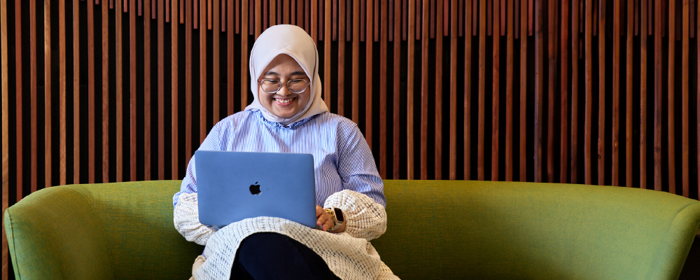 An ANU student smiling as she uses her laptop.
