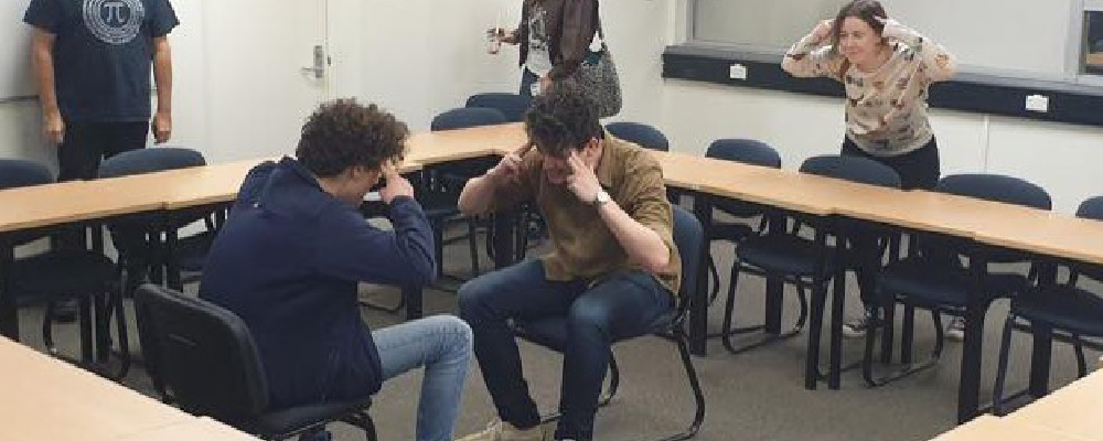 Two club ANU members sit and face each other during an Improv Society workshop.