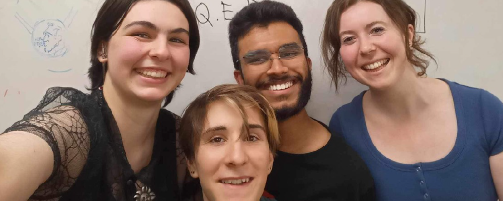 Members of the ANU Improv Society posing for a photo in front of a whiteboard.