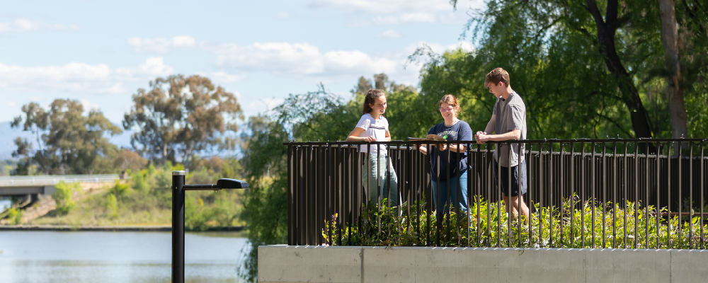 Three ANU students chat on Yukeembruk rooftop overlooking Sullivan’s Creek.