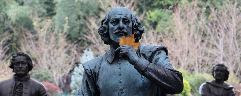 A statue of William Shakespeare, with an autumn leaf placed within the hand of the statue. 