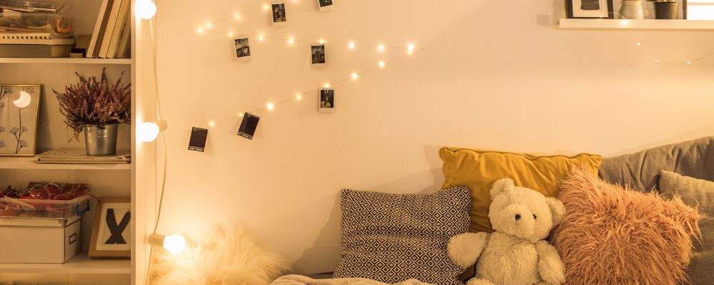 A cosy university room, decorated with pictured, a teddy bear, and fairy lights.