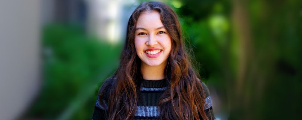 Female ANU student Kira Atkins smiles at the camera.