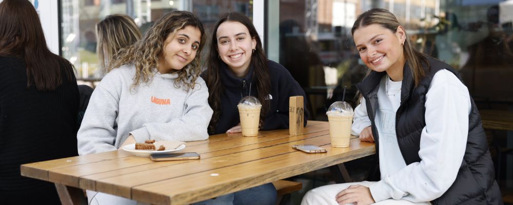 Three ANU students sitting outside at the LAB café on the ANU campus.