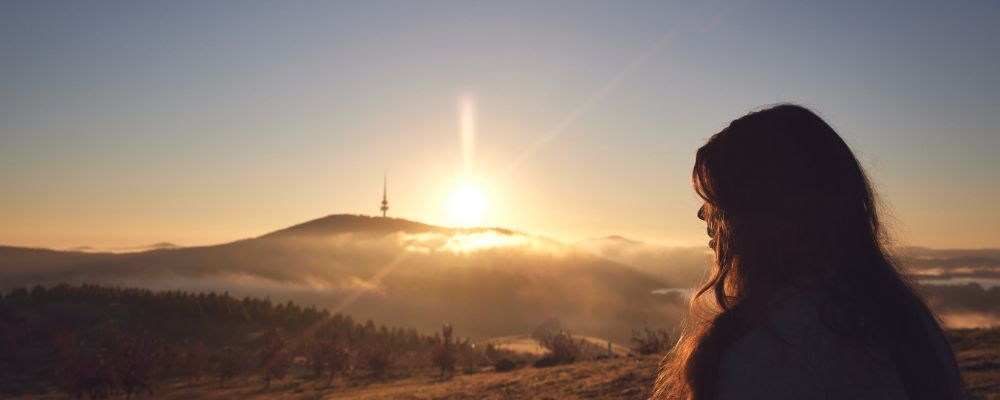 ANU student looks towards Telstra Tower at a National Arboretum lookout point.