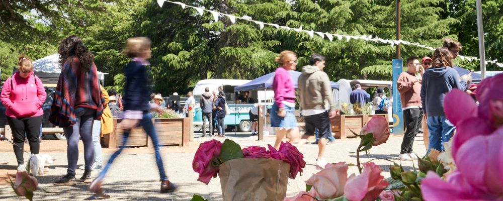 Haig Park Village Markets during spring in Canberra with flowers in the foreground.