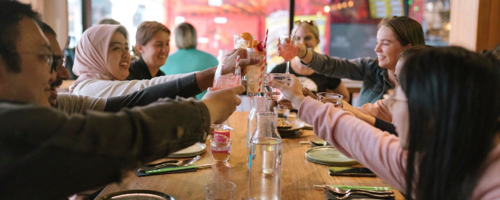 ANU students toasting with their drinks around a table in a Canberra restaurant