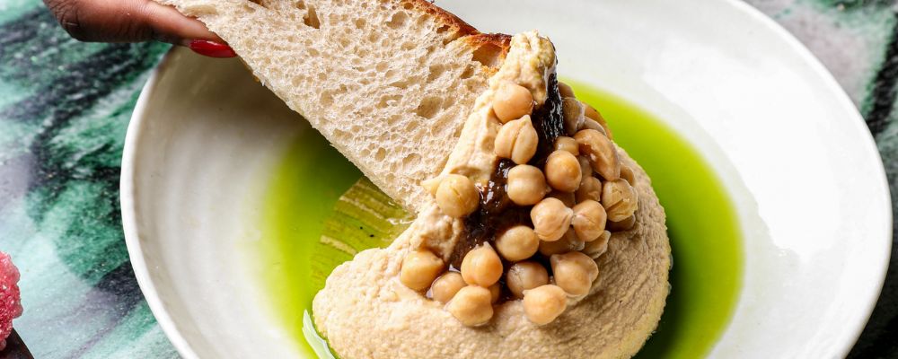 A woman dips bread into a plant-based, vegan hummus dip at Monster Kitchen and Bar in Canberra