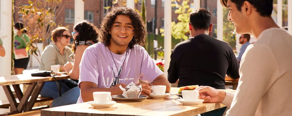 Two male ANU students relaxing and hanging out, enjoying coffee outside.
