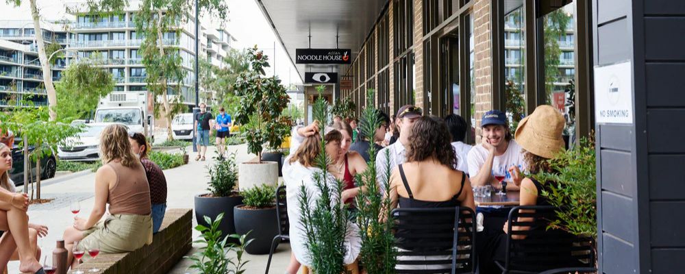 Exterior of Campbell shops and people dining and drinking outside. 