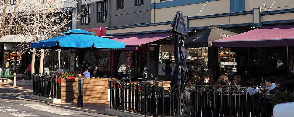 Street view of Manuka shops, with people dining outside. 