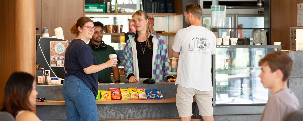 Students hanging out and working at a student residence café on campus at ANU.