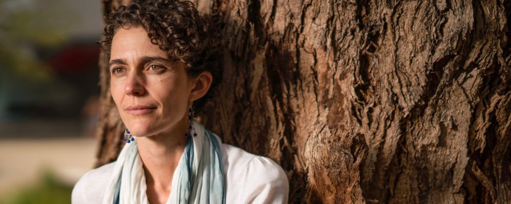 ANU researcher Marta Yebra stands with her back against an Australian native tree.