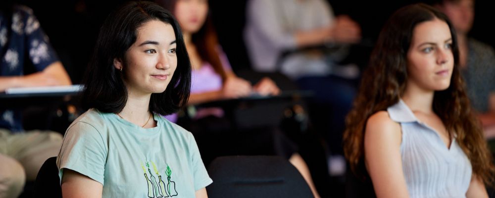 A female university student sitting in a lecture hall at ANU.