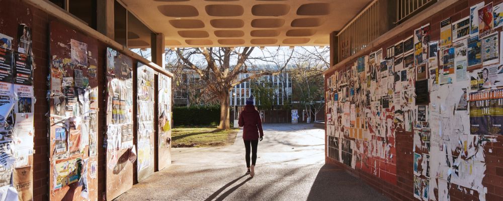 An individual walking through an underpass walkway on the ANU campus off University Avenue