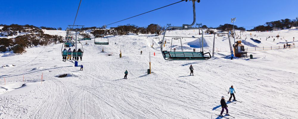 A woman wearing snow headgear and holding ski equipment on the slopes at Corin Forest