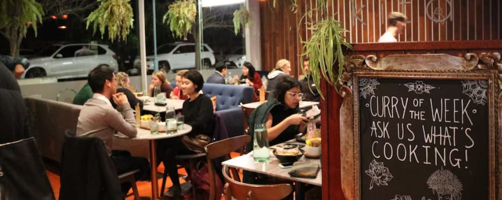 The busy interior of Kita Café at night with people eating and enjoying themselves.