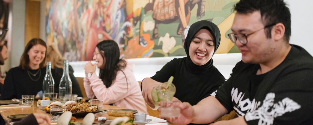 ANU students sit around a table at a restaurant in Canberra and share dinner together.