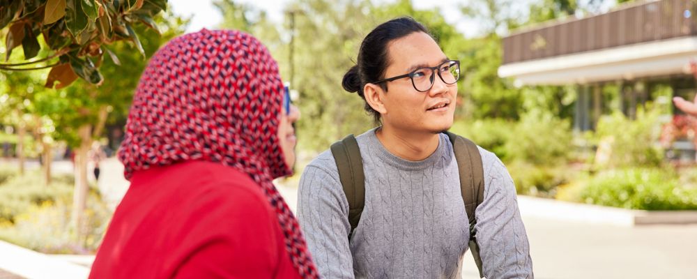 Two ANU students sit together in the Kambri precinct on campus at the Australian National University.