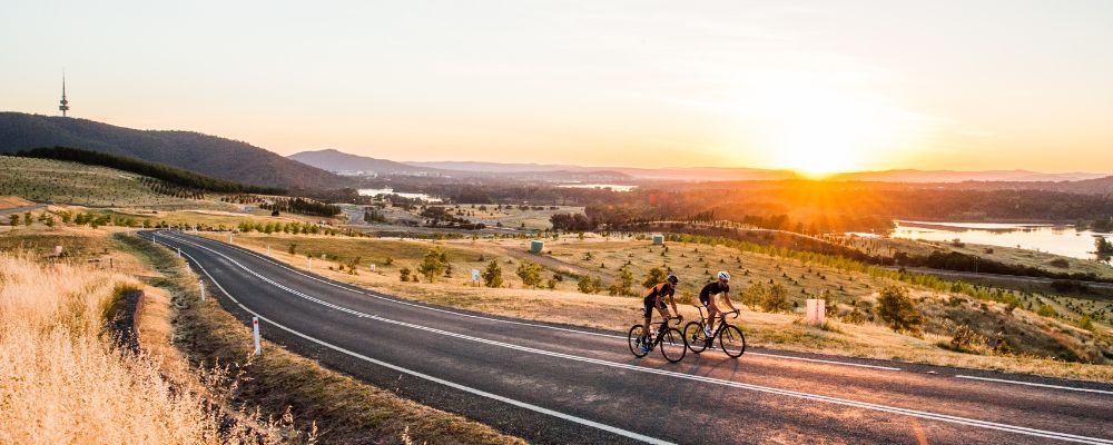 Two cyclists ride uphill over a vista at the National Arboretum in Canberra, Australia.