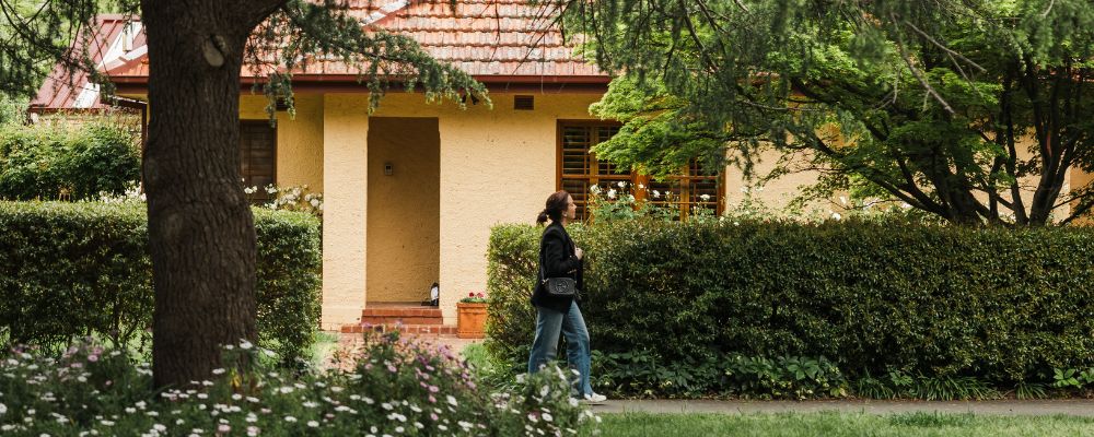 A woman walks in front of a house in the suburb of Kingston, Canberra.