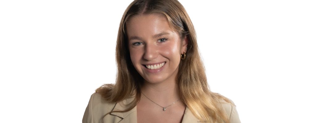 ANU student Mikayla Helms against a white background in a photoshoot setting smiling at the camera.