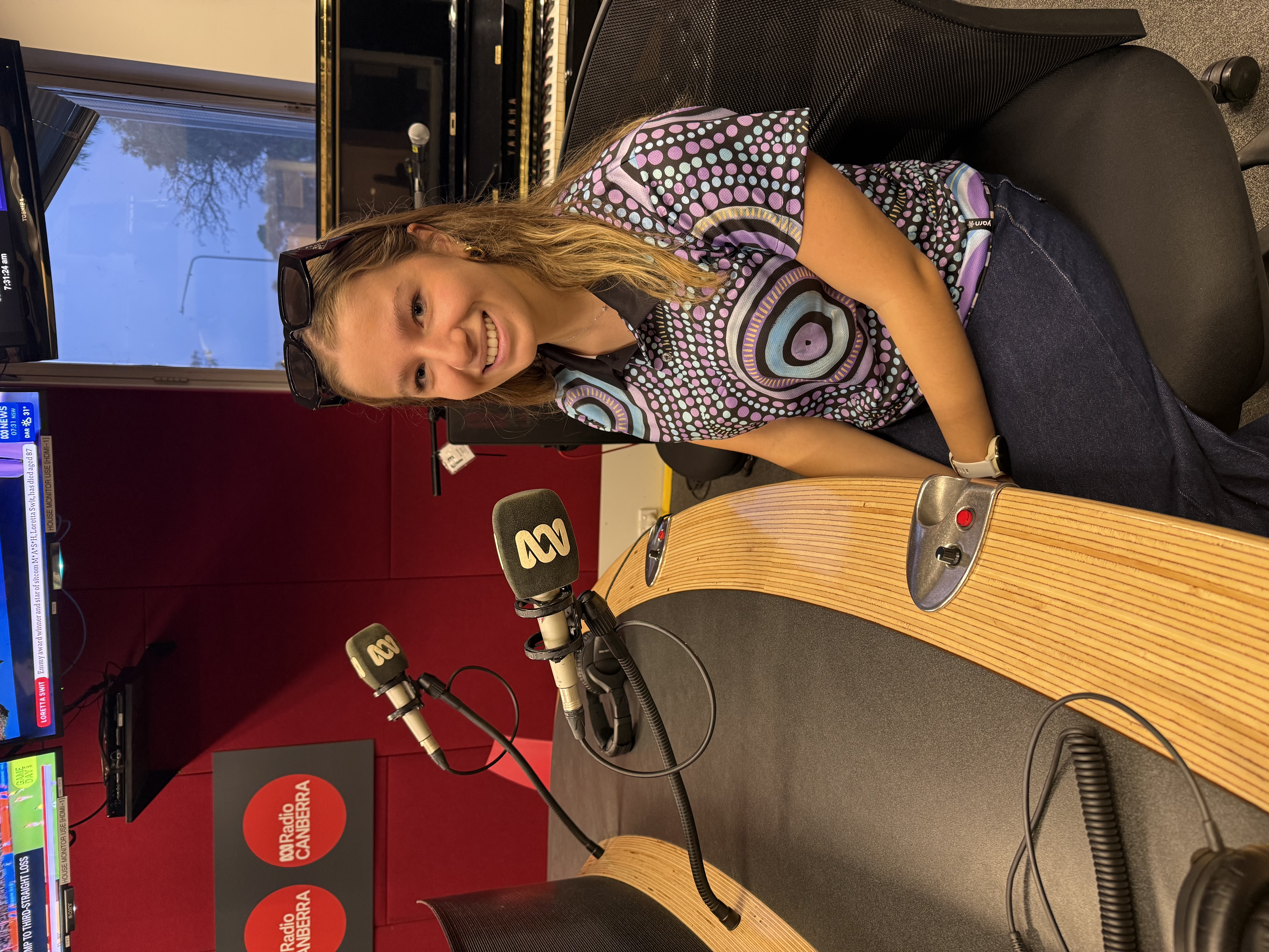 ANU student Mikayla Helms against a white background in a photoshoot setting smiling at the camera.
