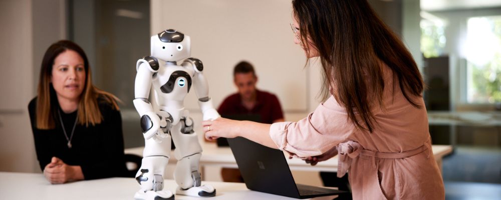 A postgraduate student at ANU analyses a robot within a tutorial setting on campus.