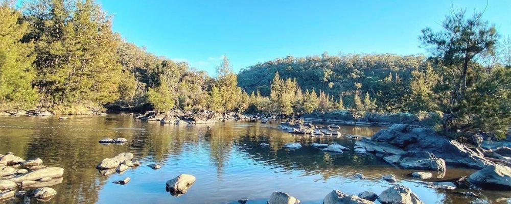 A sunny day at Kambah Pool in Canberra, showing the waterways, trees and rock formations.