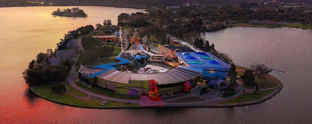 A birds eye view of the National Museum of Australia and Lake Burley Griffin at sunset.