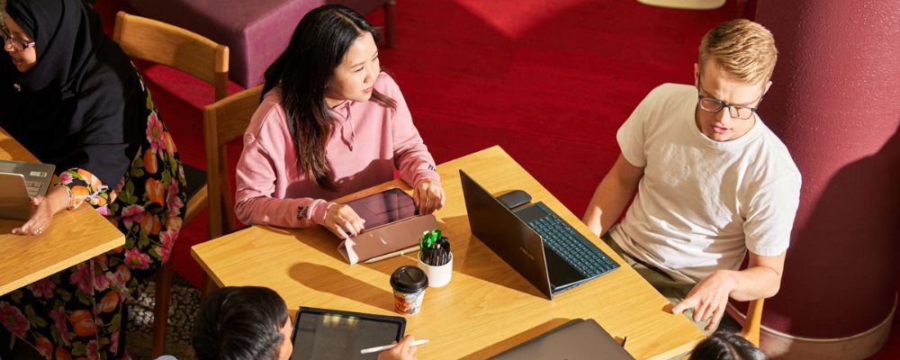 ANU postgraduate students sit together on communal study tables.