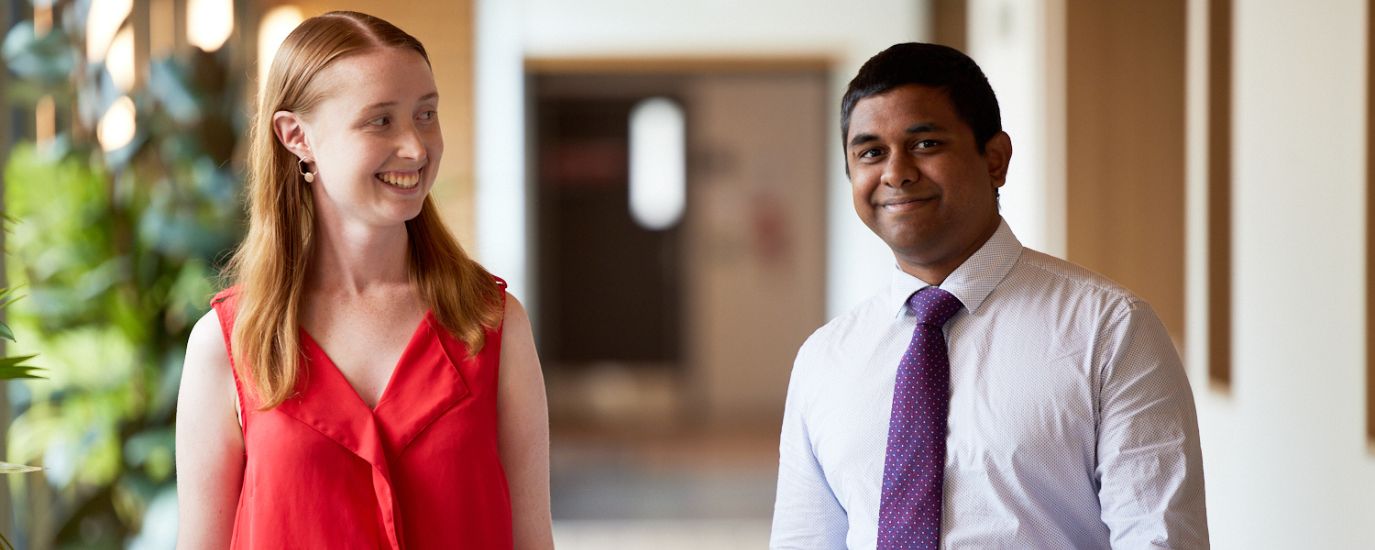 Two postgraduate students walk down a hallway on The Australian National University campus.