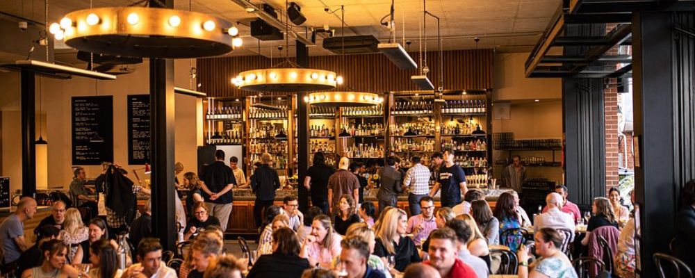 A view of the interior of Verity Lane Market with crowded tables of people eating and a busy bar.