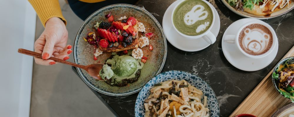 A view of a table containing mains from Tokyo Canteen as well as two hot beverages.