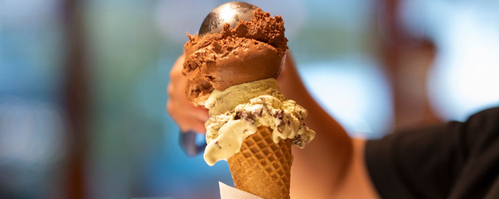 A worker at Messina scoops a double scoop of ice cream onto a waffle cone at Messina in Braddon.