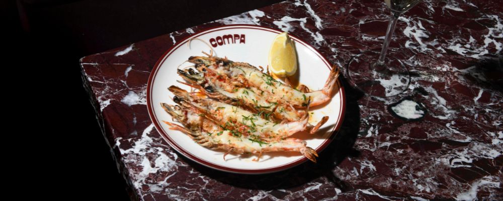 A plate of barbequed and marinated prawns sit on a plate at Compa in Canberra City.