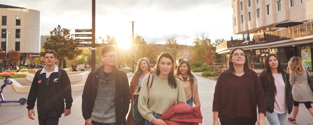 ANU students walking down University Avenue in the late afternoon together, smiling and laughing.